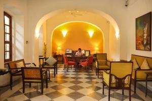 a person sitting at a table in a room with chairs at Palais De Mahe - CGH Earth in Puducherry
