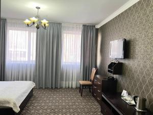 Pokój hotelowy z łóżkiem, krzesłem i telewizorem w obiekcie Sultan w mieście Biszkek