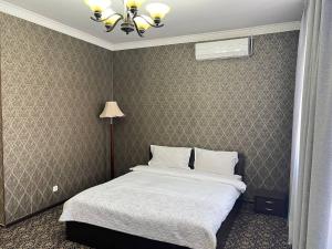 sypialnia z łóżkiem i lampką w obiekcie Sultan w mieście Biszkek