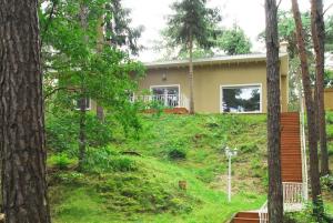 une maison sur une colline herbeuse avec des arbres dans l'établissement Ferienhaus Waldidyll, à Zempin