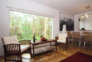 une salle à manger avec une table, des chaises et une grande fenêtre dans l'établissement Ferienhaus Waldidyll, à Zempin