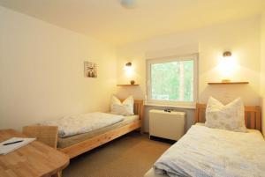 Cette chambre comprend 2 lits, une table et une fenêtre. dans l'établissement Ferienhaus Waldidyll, à Zempin