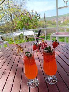 two cocktails on a wooden table with strawberries in them at Casa Tonyza in Cisnădie