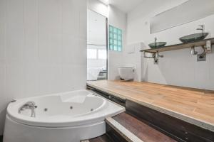 La salle de bains est pourvue d'une baignoire blanche et de parquet. dans l'établissement Grand Loft Spacieux Paris 8 Pers WIfi CDG, à Bagnolet