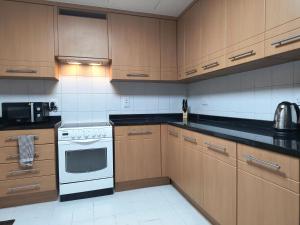 a kitchen with wooden cabinets and a white stove top oven at Trinity Holiday Homes - Sheikh Zayed Road Near to Financial Center Metro Station in Dubai