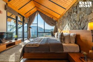 a bedroom with a bed and a stone wall at StayVista at Shai Sher Estate with Bonfire, BBQ and Lawn in Shimla