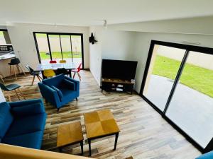 ein Wohnzimmer mit blauen Stühlen, einem TV und einem Tisch in der Unterkunft Beach house in Gouville-sur-Mer