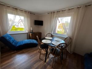 a dining room with a table and chairs and two windows at Dom Wczasowy Dorja in Jastarnia