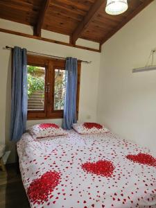 Un dormitorio con una cama con corazones rojos. en Zimmer In The Garden en Karmiel