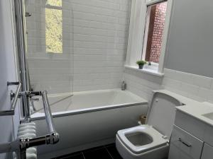 a bathroom with a white tub and a toilet at Beautifully Lit Airy 1-Bed Apartment in Liverpool in Liverpool