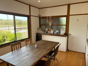 a dining room with a wooden table and windows at ikibase Guest House in Iki