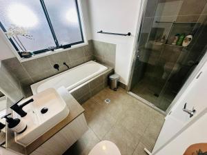 La salle de bains est pourvue d'une baignoire, d'un lavabo et d'une douche. dans l'établissement A Private Ensuite with AC and TV, à Austral