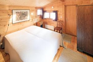 プーマラにあるOkkolan Lomamökitの木製の部屋に白いベッドが備わるベッドルーム1室