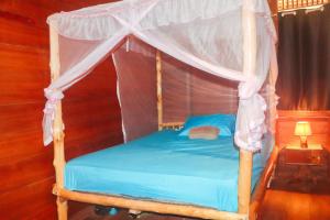 a bedroom with a canopy bed with blue sheets at Mentawai Ebay Playground Surfcamp in Masokut