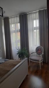 Schlafzimmer mit einem Bett, einem Stuhl und Fenstern in der Unterkunft An der Neiße in Görlitz