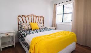 Lavender Lane Country Cottages في Kenilworth: غرفة نوم بسرير وبطانية صفراء ونافذة