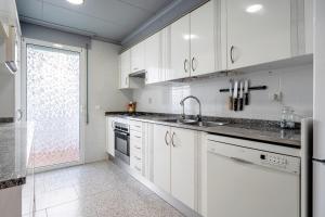 Casa García في L'Aldea: مطبخ مع دواليب بيضاء ومغسلة