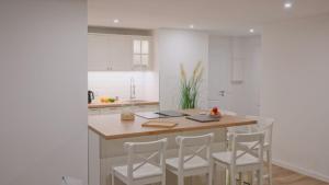 a kitchen with a island with four white stools at Land-Apartments Netphen in Netphen +29 photos