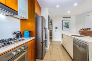 une cuisine avec un réfrigérateur et des armoires en acier inoxydable dans l'établissement Casuarina Resort Style 3BR Apartment by uHoliday, à Casuarina 31 autres photos