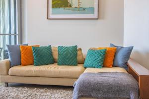 - un canapé avec des oreillers colorés dans le salon dans l'établissement Casuarina Resort Style 3BR Apartment by uHoliday, à Casuarina