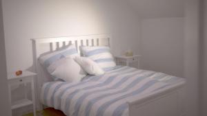 a white bed with blue and white sheets and pillows at Land-Apartments Netphen in Netphen