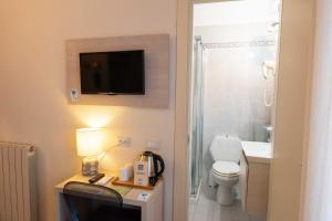 a bathroom with a toilet and a tv on the wall at Hotel Pardini in Viareggio
