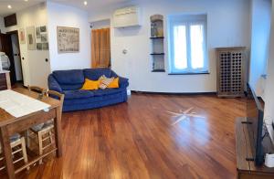 sala de estar con sofá azul y suelo de madera en casa porticciolo, en Génova