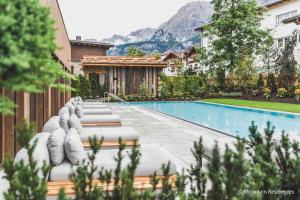 a house with a swimming pool with mountains in the background at Bergresort Zugspitze Ehrwald by ALPS RESORTS in Ehrwald