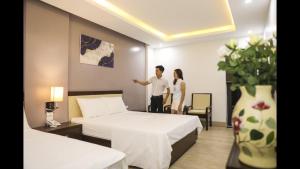 岑山的住宿－Khách Sạn Sen Biển Sầm Sơn，一名男子和女子站在带两张床的酒店房间