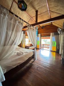 een slaapkamer met een bed met gordijnen en een houten vloer bij Shaya’s Green Hideaway 