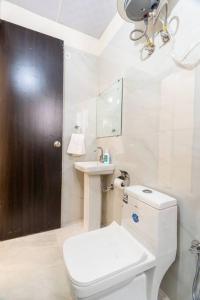 a white bathroom with a toilet and a sink at Homlee-Vasundhara 2BHK Flat with Kitchen parking in Ghaziabad