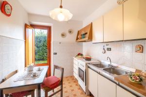 eine Küche mit weißen Schränken, einer Spüle und einem Tisch in der Unterkunft Villino Carla Few KM From Lucca - Happy Rentals in Lucca