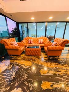 Arunsakhon luxury condo في Ban Khok Kham: غرفة معيشة مع أثاث برتقالي ونوافذ زجاجية