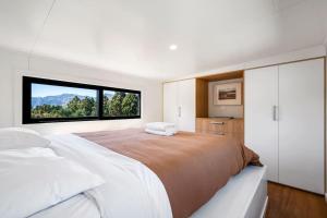 ein Schlafzimmer mit einem großen Bett und einem großen Fenster in der Unterkunft Tiny Home on 1 Acre Land in Picturesque Hawea Flat in Hawea Flat