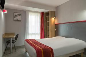 a bedroom with a bed and a desk and a window at The Originals City, Hôtel Albizia, Sarlat-la-Canéda in Sarlat-la-Canéda
