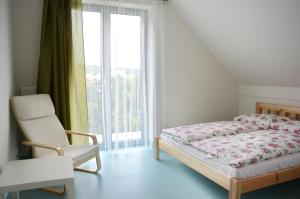a bedroom with a bed and a chair and a window at Mezi Stromy in Brno