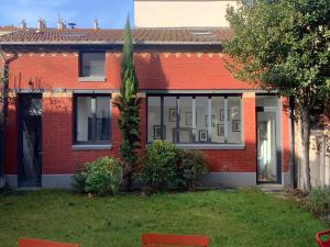 een rood bakstenen huis met een raam bij L'Atelier - Boulogne - Roland Garros, Parc des Princes, JO in Boulogne-Billancourt