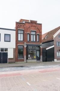 a brick building with windows on a street at Pakhuis aan de Zaan in Wormerveer