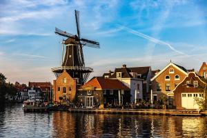 a windmill in a town next to a body of water at Amrâth Grand Hotel Frans Hals in Haarlem