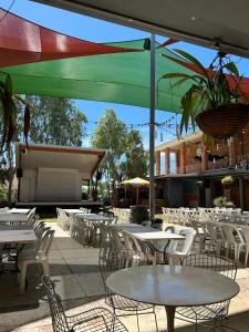 un patio con mesas blancas, sillas y sombrillas en North Gregory Hotel en Winton