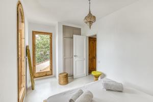 Un dormitorio blanco con una cama y un espejo. en Villa la Barrufa, en S'Agaró