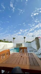 - une table et des chaises en bois à côté de la piscine dans l'établissement Al Wahid Holiday Homes, à Dubaï