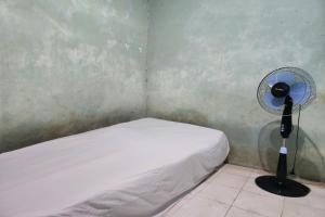 a small room with a bed and a fan at SPOT ON 93894 Jamil Homestay Syariah in Plosobegem