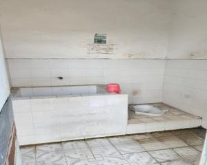 a dirty white tiled bathroom with a toilet at SPOT ON 93894 Jamil Homestay Syariah in Plosobegem