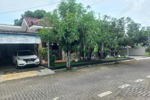 a car parked in front of a house with trees at OYO 93892 Homestay Koe Syariah in Purwokerto