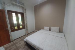 a bedroom with a white bed and a window at OYO 93892 Homestay Koe Syariah in Purwokerto