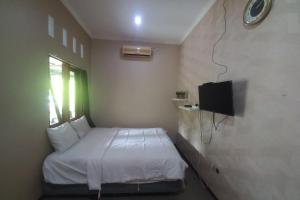 Dormitorio pequeño con cama y TV en OYO 93892 Homestay Koe Syariah en Purwokerto