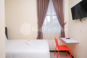 een slaapkamer met een bed, een rode stoel en een raam bij Griya Loka 2 Syariah Near Simpang Lima Mitra Reddoorz in Semarang