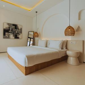 ein Schlafzimmer mit einem großen Bett und Hängelampen in der Unterkunft The Serendipity Palms Villa by Hombali in Canggu