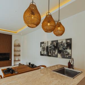 eine Küche mit drei Hängelampen und einem Waschbecken in der Unterkunft The Serendipity Palms Villa by Hombali in Canggu